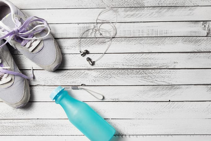 Overhead shot of workout shoes, water bottle, and ear buds.