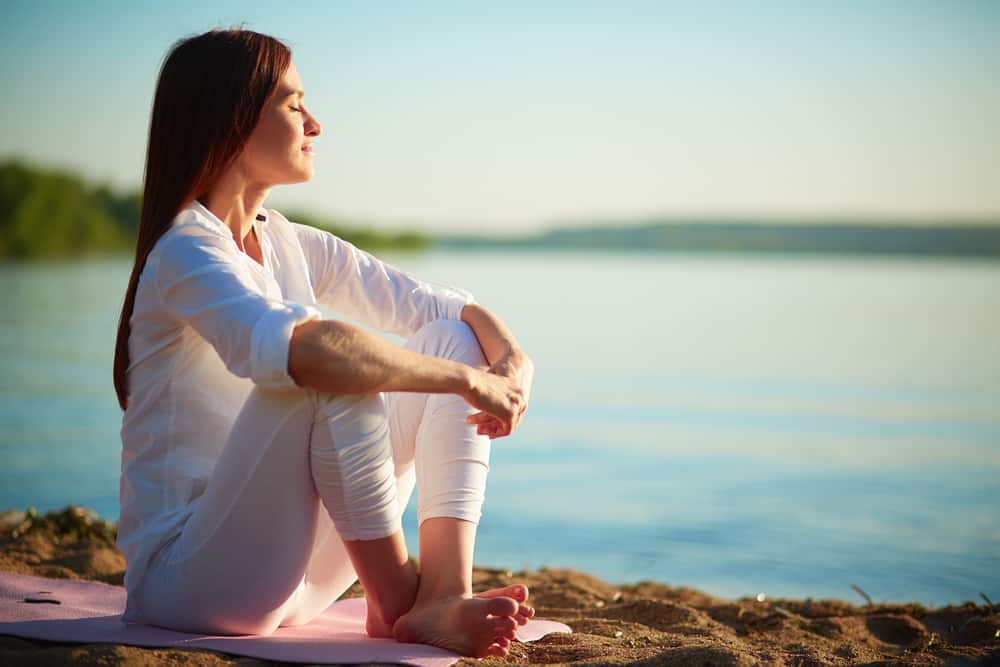 Woman sitting on a beach relaxed and meditating. 