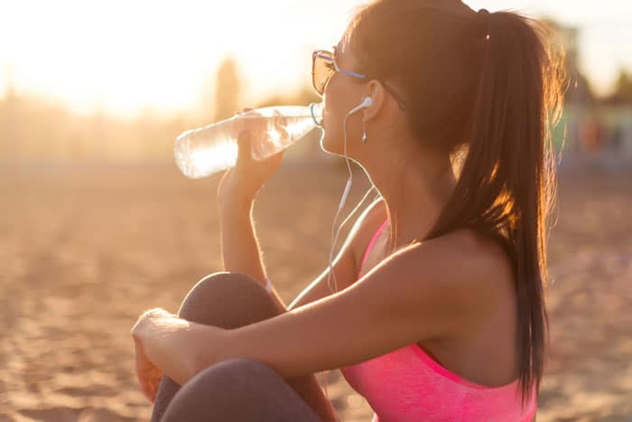 girl drinking water on the beach