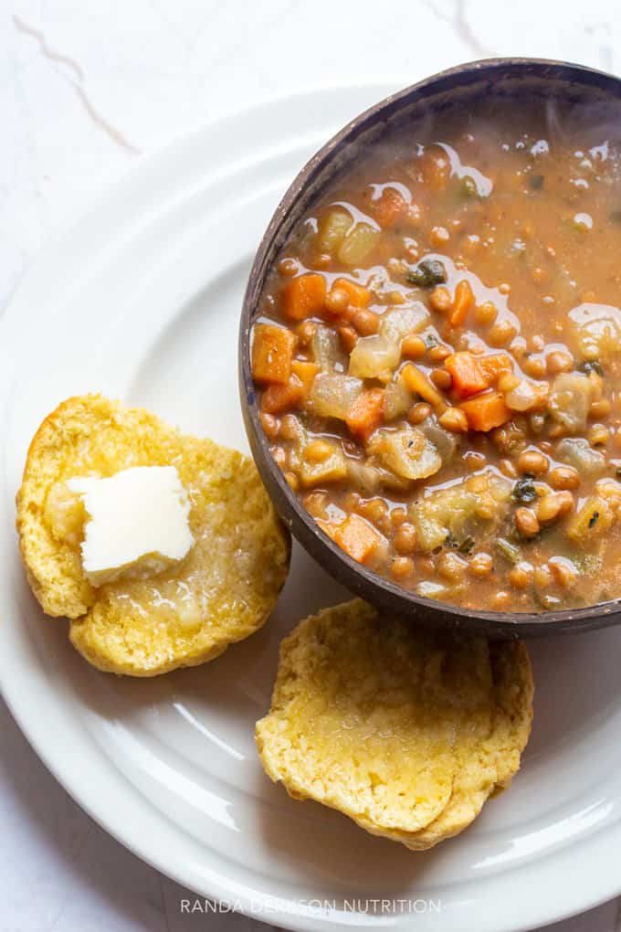 gluten free dinner rolls with a pat of butter with a bowl of lentil soup