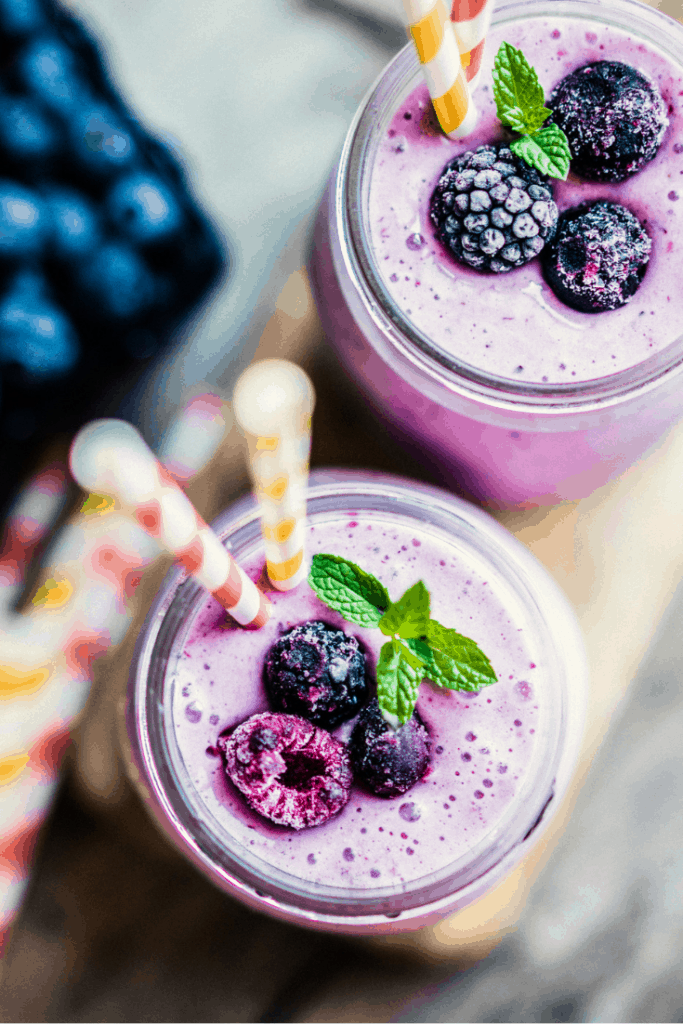 delicious purple, wildberry smoothies with frozen berries and mint on top.