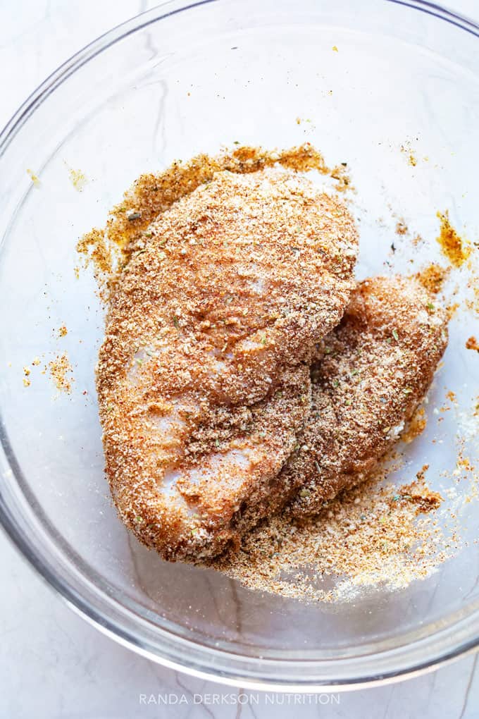 chicken being dredged in a bowl of almond flour and fajita spices