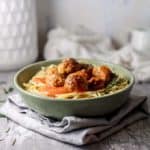 hidden vegetables in beef meatballs laying over pasta in a green bowl