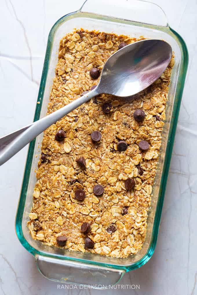 peanut butter bars being pressed into a pan with the back of the spoon