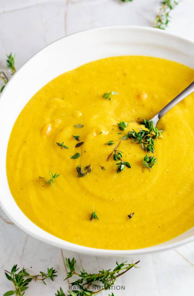 vegan cauliflower soup in a white bowl garnished with fresh thyme