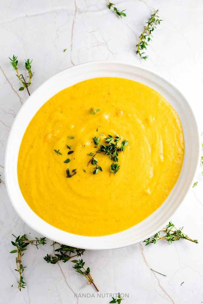 vegan cauliflower soup in a white bowl garnished with fresh thyme