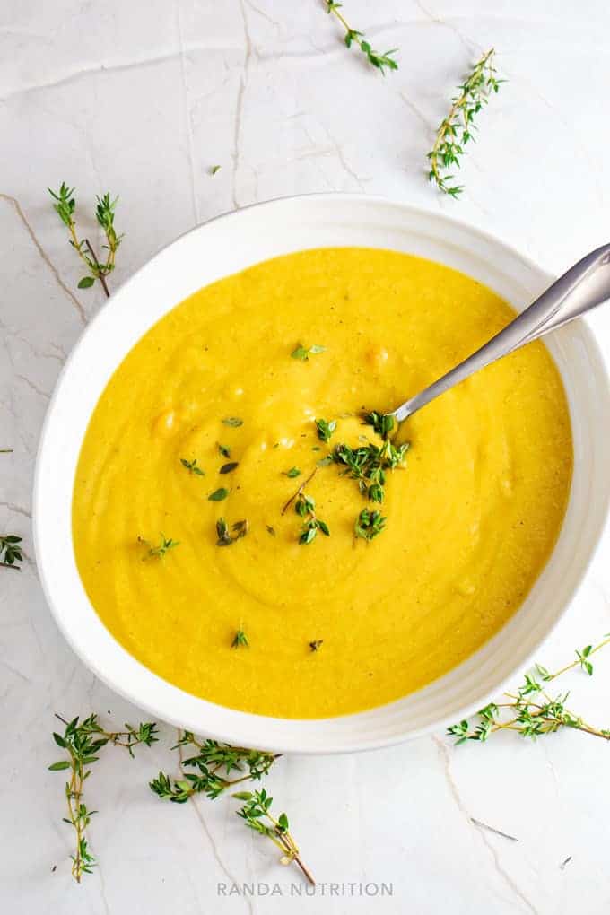 vegan cauliflower soup in a white bowl garnished with fresh thyme