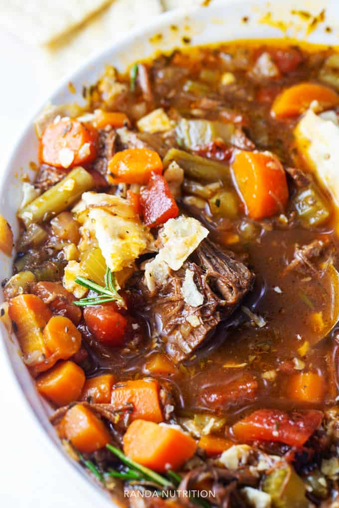 close up of pot roast soup with carrots, celery, green beans, fresh herbs, and leftover brisket.