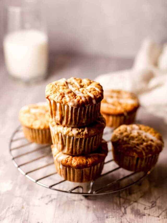 a stack of these gluten-free apple muffins on a wire cooling rack with a glass jug of milk in the background