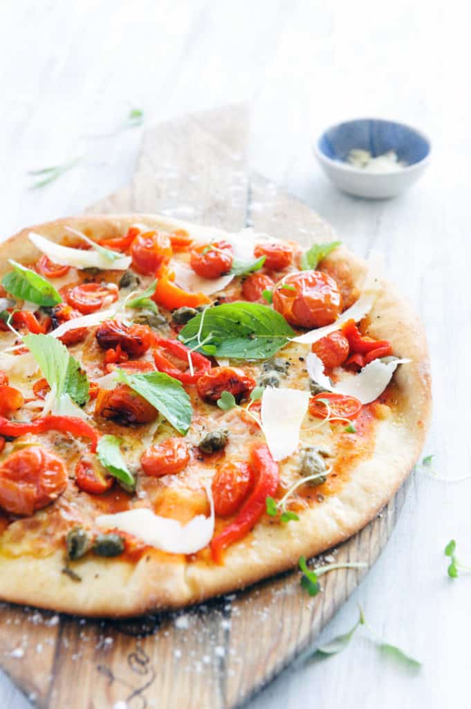 roasted tomatoes and basil on top of a healthy pizza crust