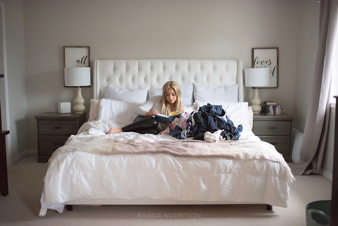 woman laying in bed practicing self care while letting laundry wait