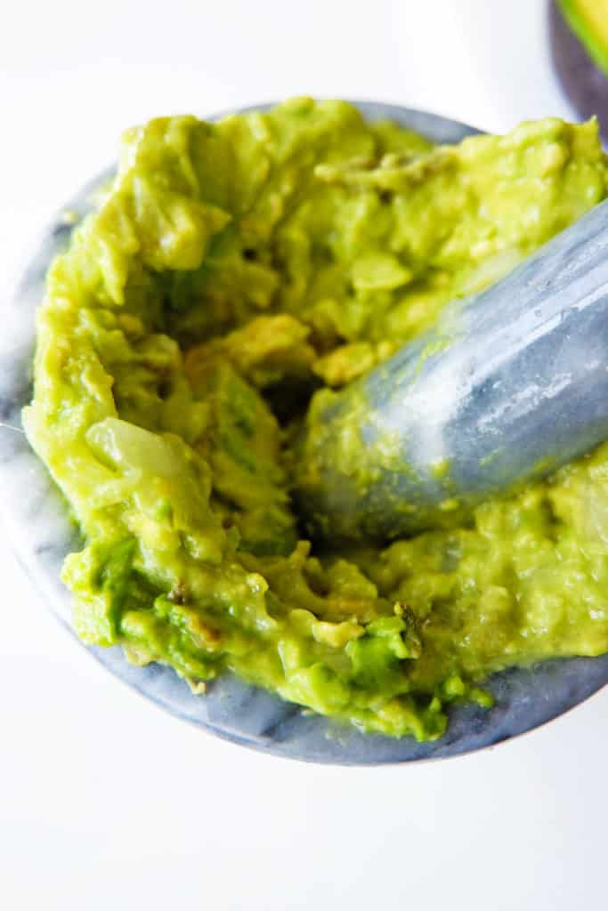 healthy guacamole being mashed together in a pestle and morter