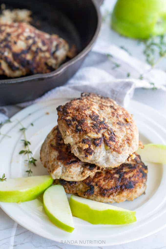 homemade chicken apple sausage in a cast iron skillet and plated with apples