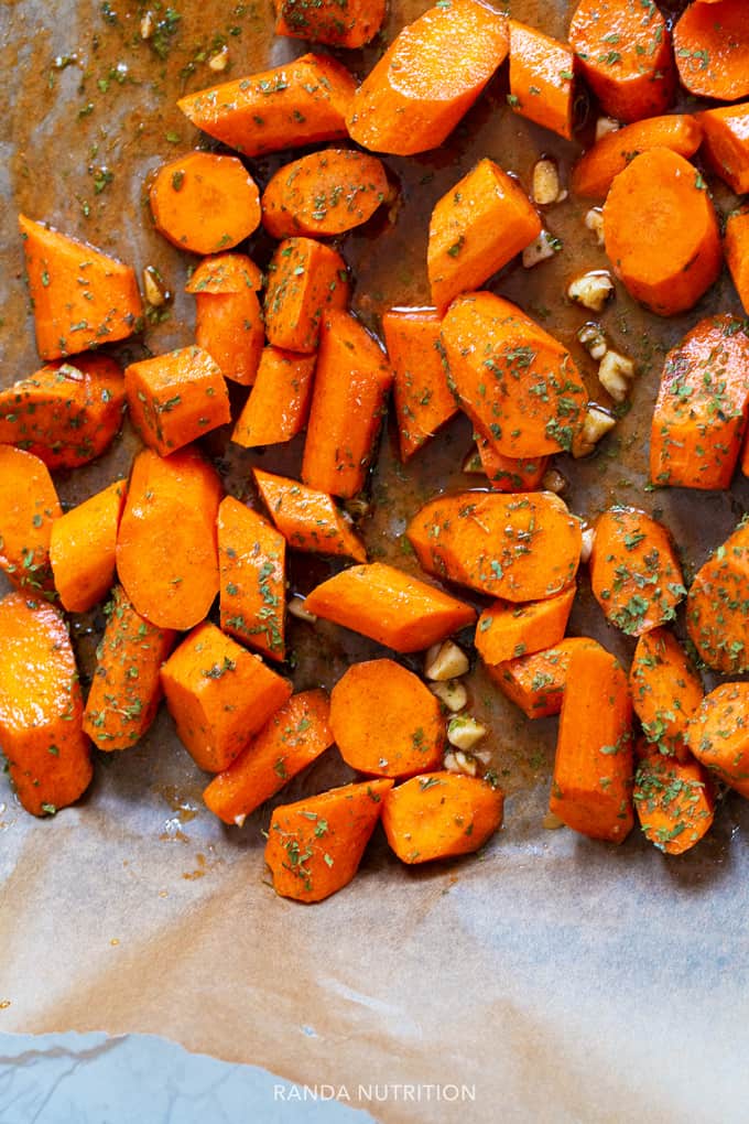 carrots tossed with spices on a sheet pan before being roasted