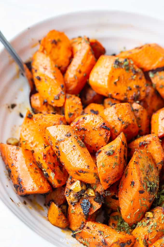 carrots with moroccan spices in a bowl that were roasted on a sheet pan