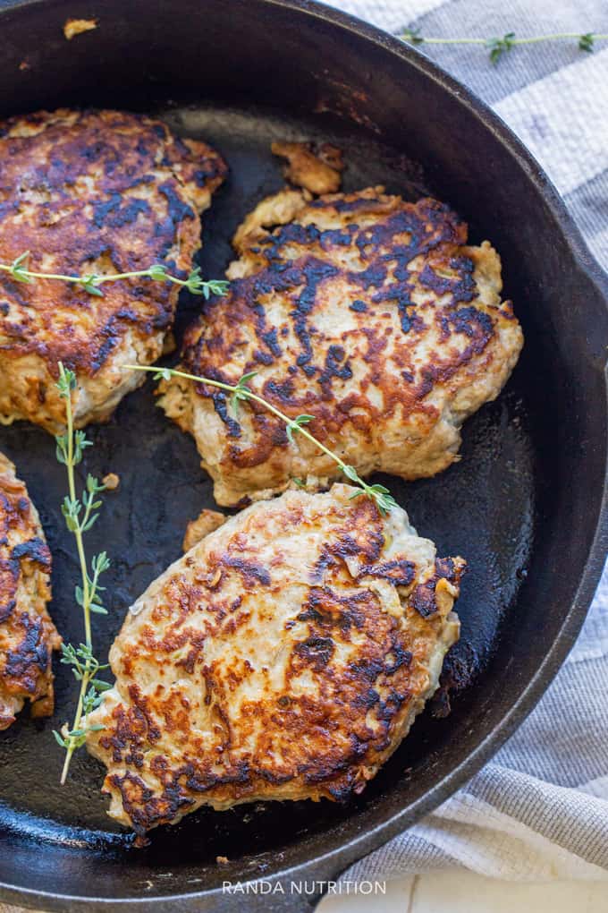 chicken apple sausages in a cast iron skillet with fresh thyme