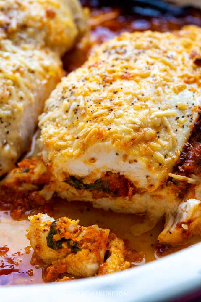 Cheesy stuffed chicken with romesco sauce, mozzarella, and spinach sliced into to reveal the center