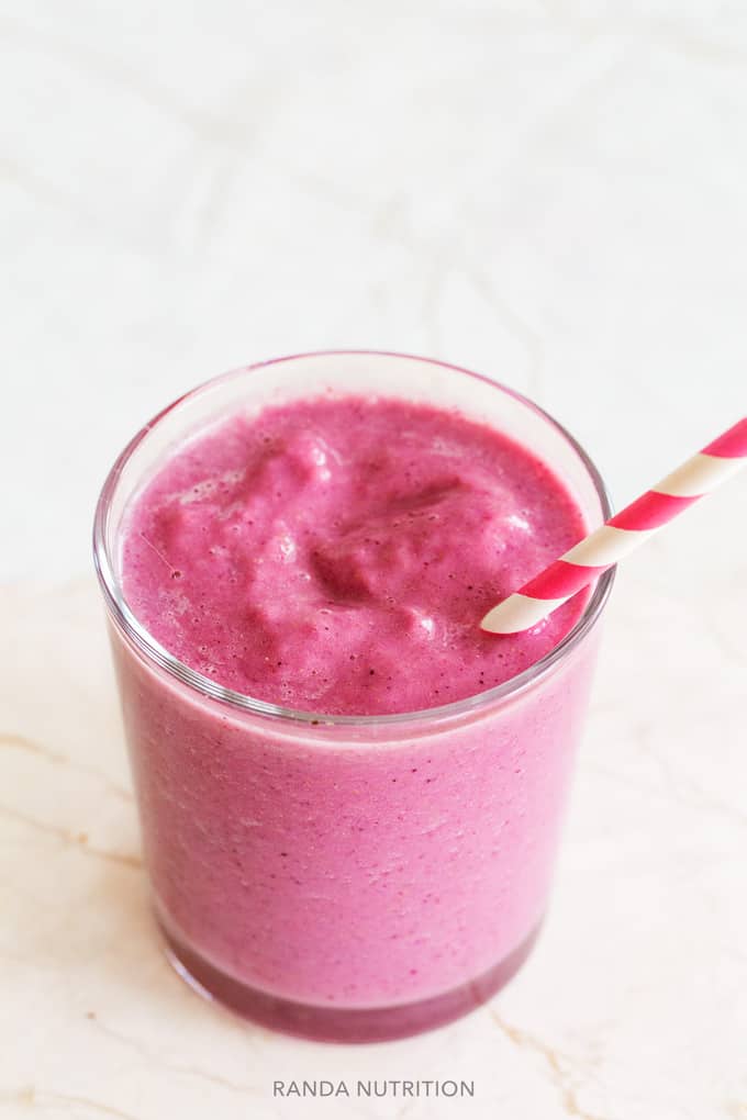 cauliflower strawberry smoothie in a small glass and paper straw