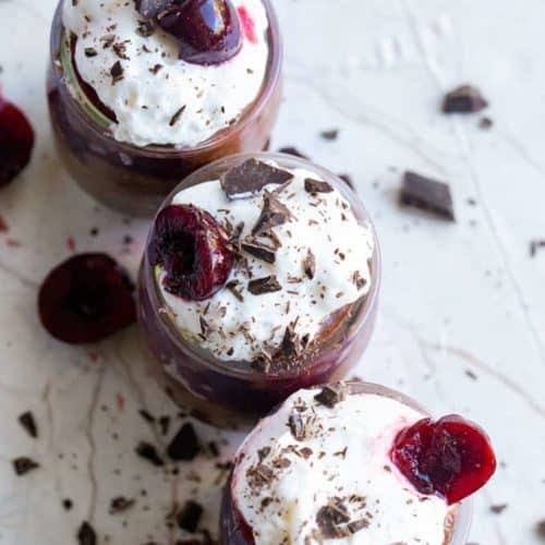 cherry chocolate chia pudding topped with coconut whip cream and chocolate flakes