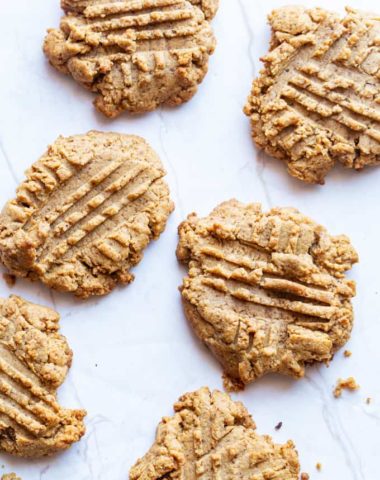 freshly baked almond butter cookies on a marble slab with crumbs