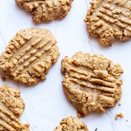 freshly baked almond butter cookies on a marble slab with crumbs