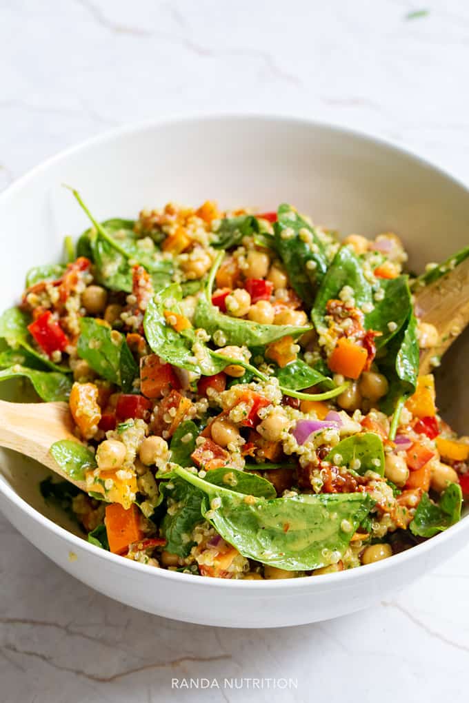 spinach quinoa chickpea salad in a white bowl