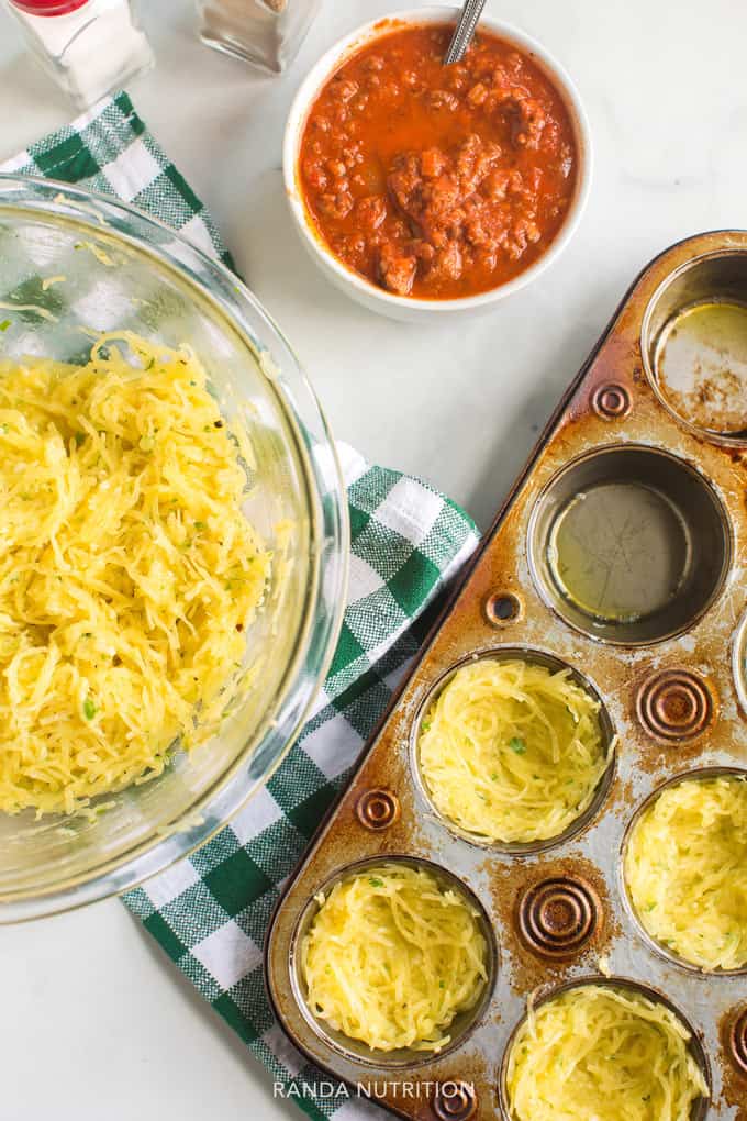 spaghetti squash pressed into a muffin tin with a side of spaghetti sauce