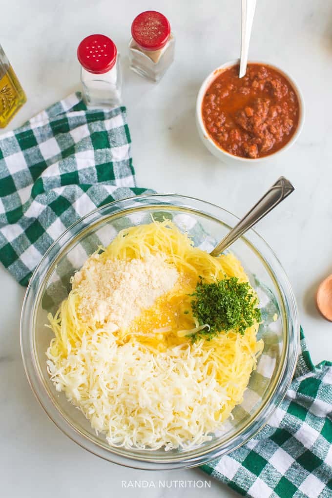 spaghetti squash, parmesan cheese, parsley mixed in a bowl with a side of spaghetti sauce