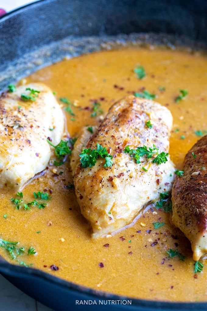 Side view of roasted chicken breasts in a coconut curry sauce topped with cilantro