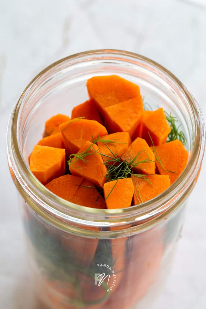 peeled and sliced carrots and dill weed in a mason jar before pickling