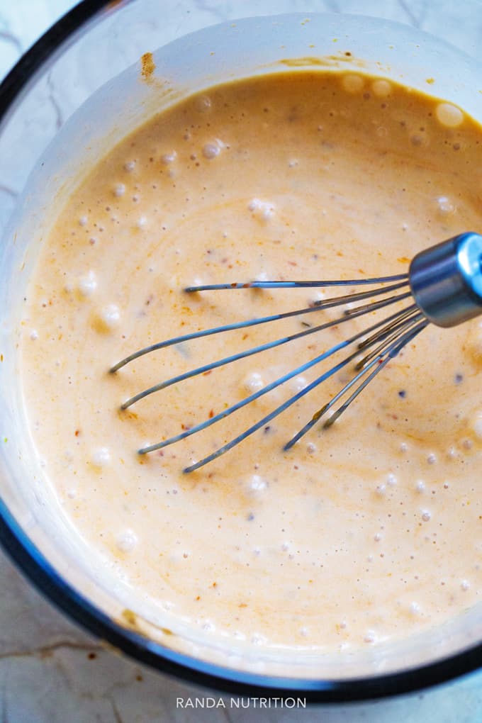 coconut curry sauce being whisked in a glass bowl.