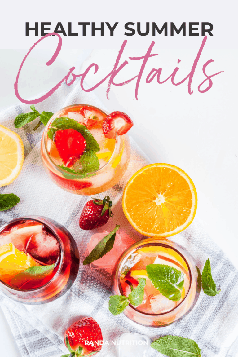 healthy summer cocktails on a white marble background and topped with fruit and mint leaves