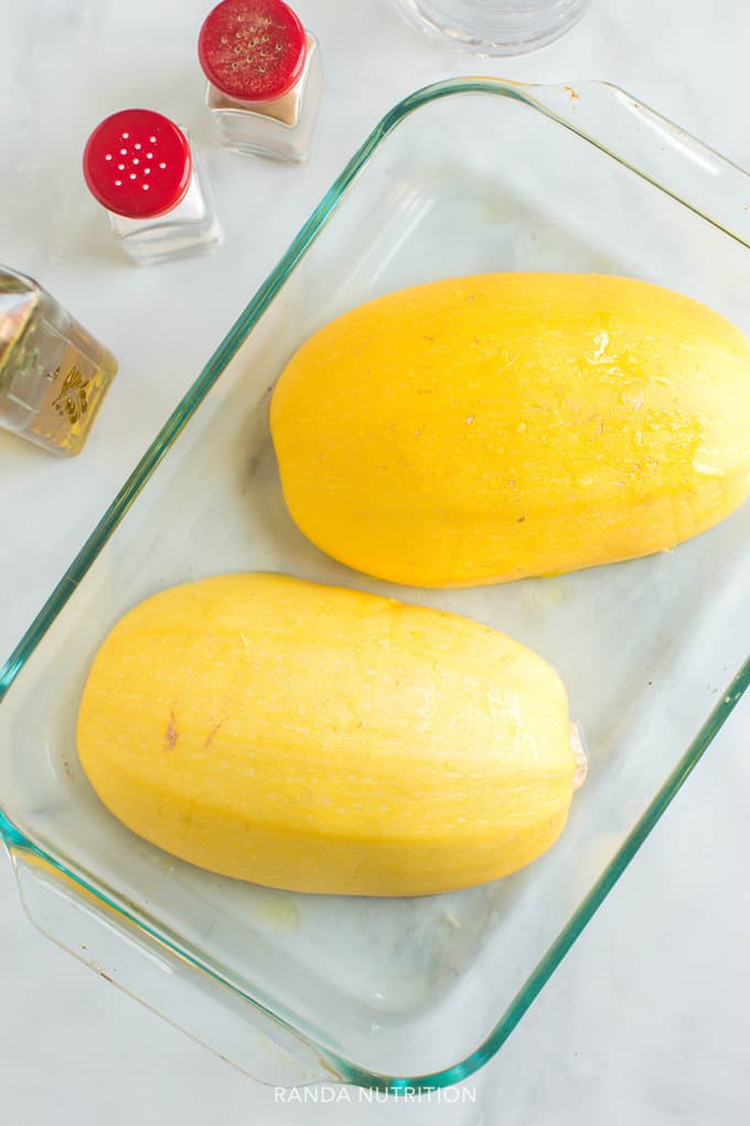 spaghetti squash face down in water about to be steamed in the oven