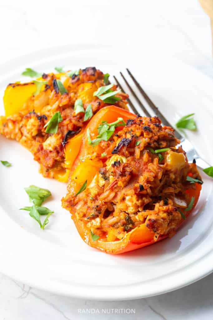 rice stuffed chicken peppers on a white plate garnished with chopped cilantro