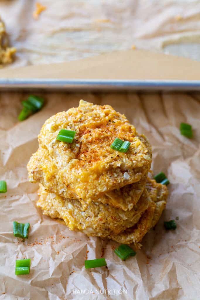 cauliflower patties stacked on each other topped with green onion