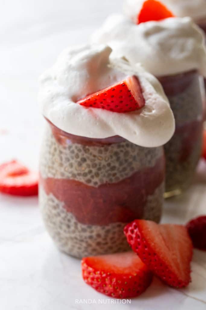 close up of a chia seed pudding in a petit jar with a layer of strawberry rhubarb sauce in the middle.