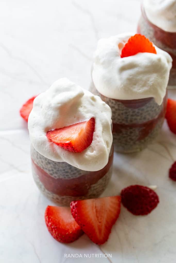 coconut whipped cream on top of a chia seed pudding with sliced strawberries