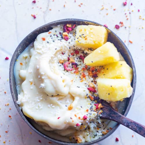 Homemade dairy free ice cream in a coconut bowl topped with pineapples and coconut