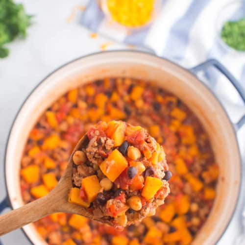 Wooden spoon close up of cooked turkey chili with butternut squash