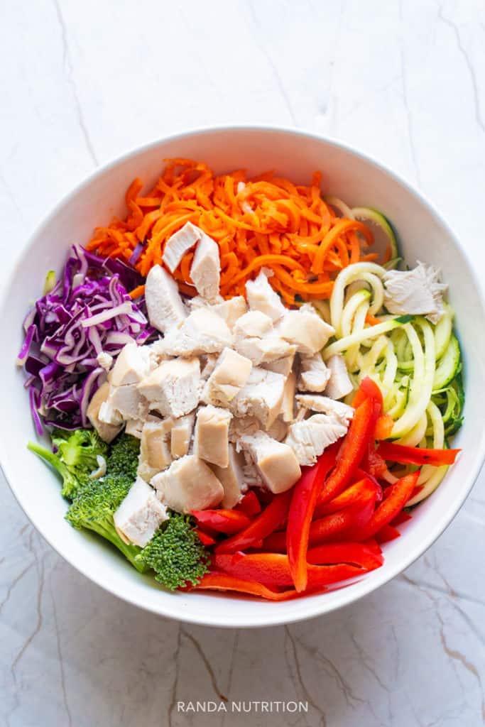 diced chicken, vegetable noodles, peanut sauce in a bowl