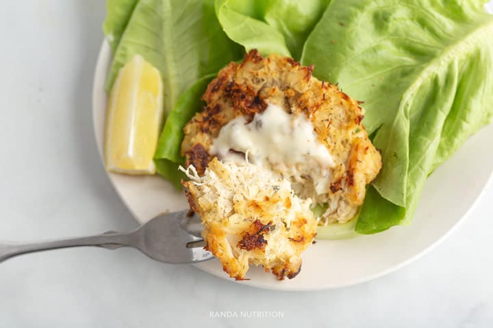 a fork pulling down a fresh crab cake showing how flakey it is