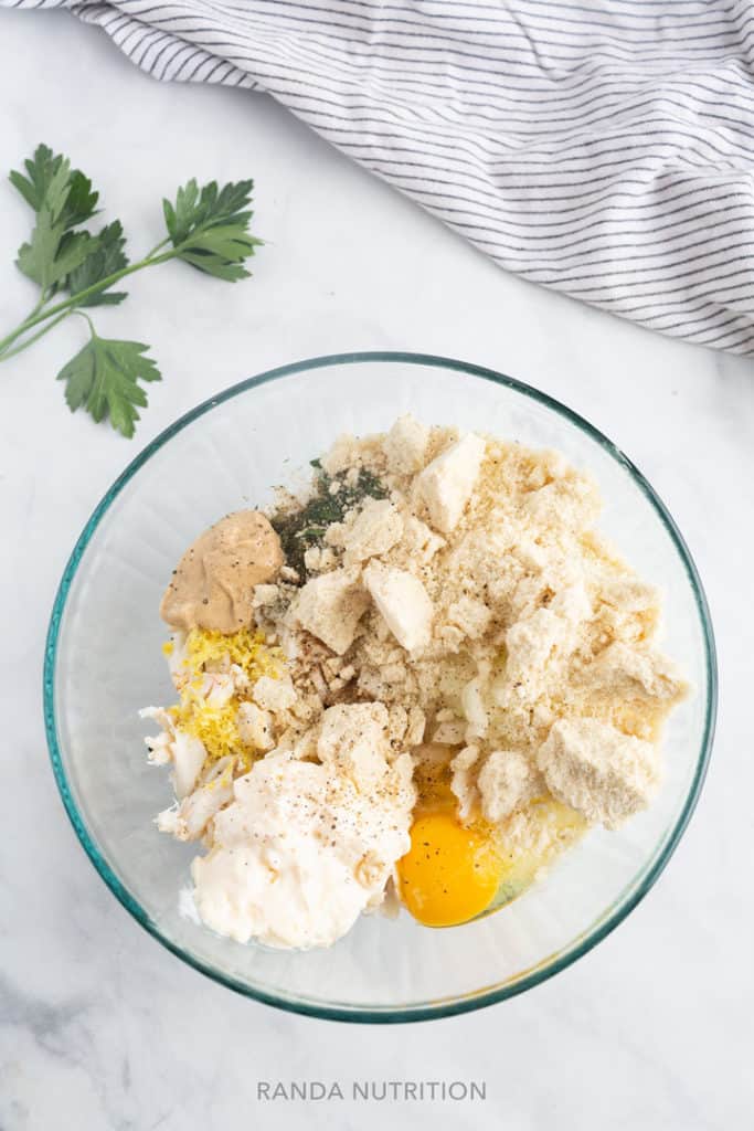 a mixing bowl full of crab, almond flour, eggs, lemon, and mayo