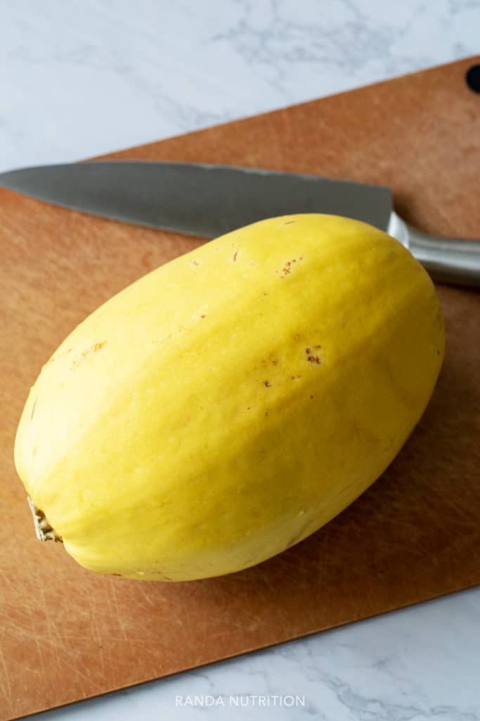 whole spaghetti squash on a cutting board with a knife