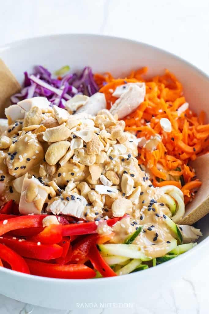 cashews, bell peppers, zucchini noodles, and carrot noodles in a bowl