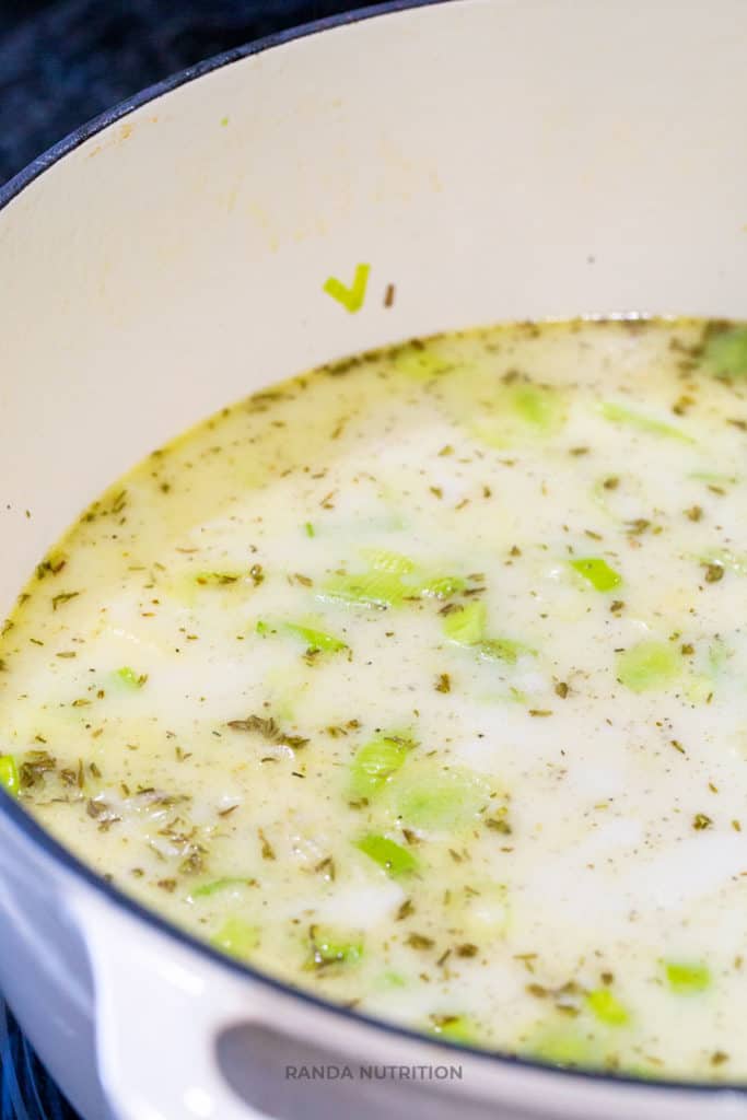 coconut milk, thyme, leeks, and potatoes boiling in a dutch oven