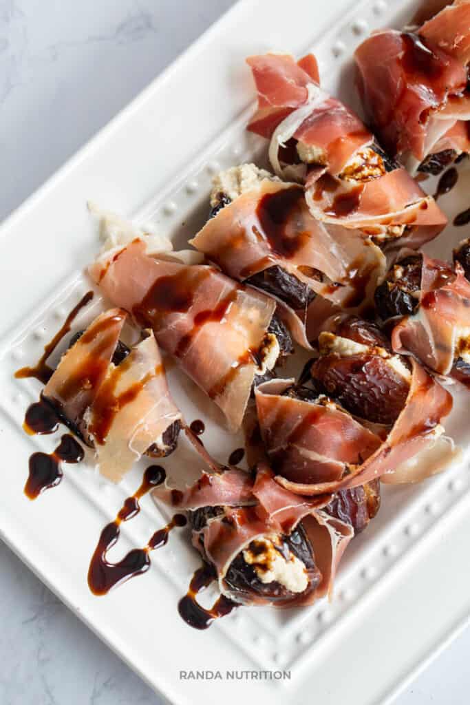 close up of a balsamic glaze being drizzled over prosciutto wrapped dates