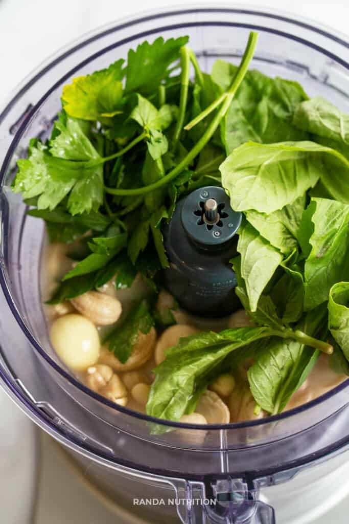 basil, parsley, garlic and cashews about to be blended in a food processor