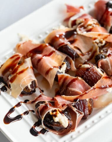 stuffed dates with a balsamic reduction drizzled over top of a white platter