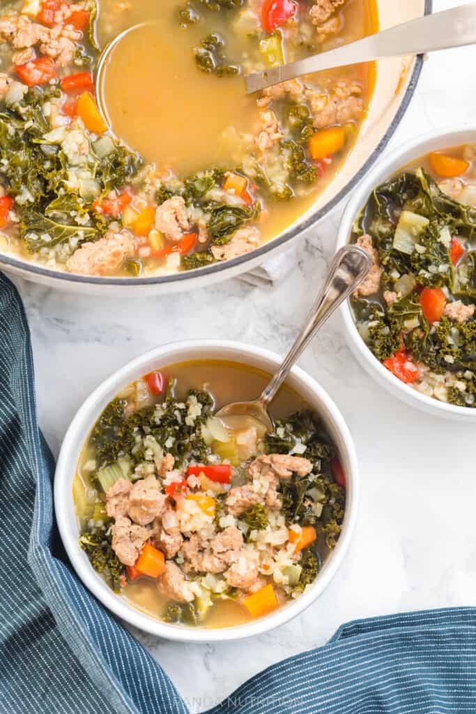 multiple servings of this healthy kale and sausage soup served in white bowls