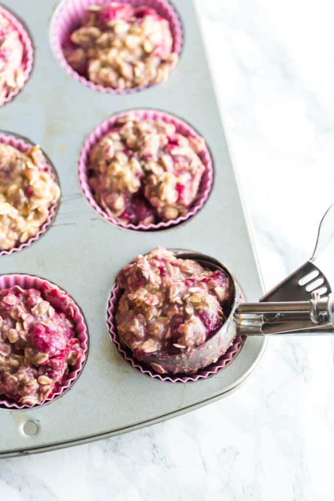 cookie scoop to add muffin batter to a muffin tin lined with silicone liners